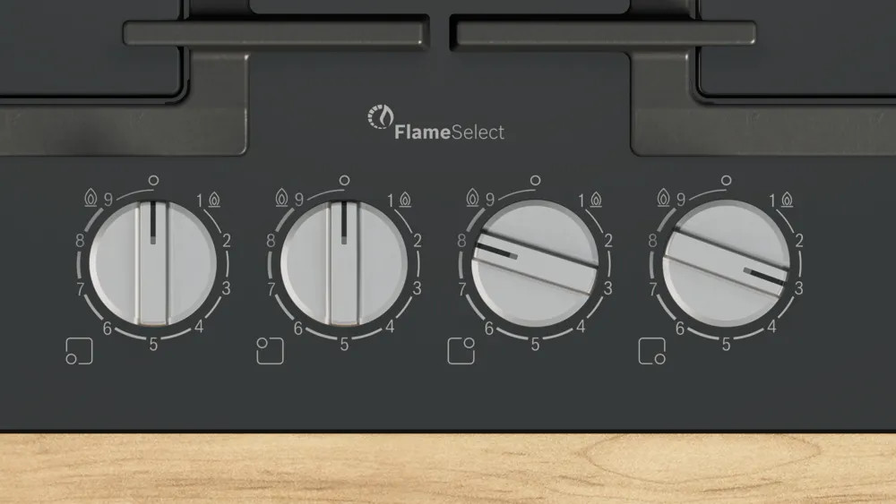 Zbliżenie pokręteł kuchenki gazowej z logo FlameSelect. Widoczne są liczby na pokrętłach.