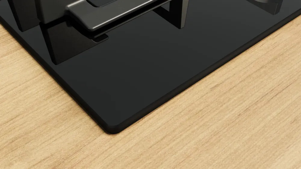 Zbliżenie rogu czarnej kuchenki gazowej na drewnianej powierzchni.