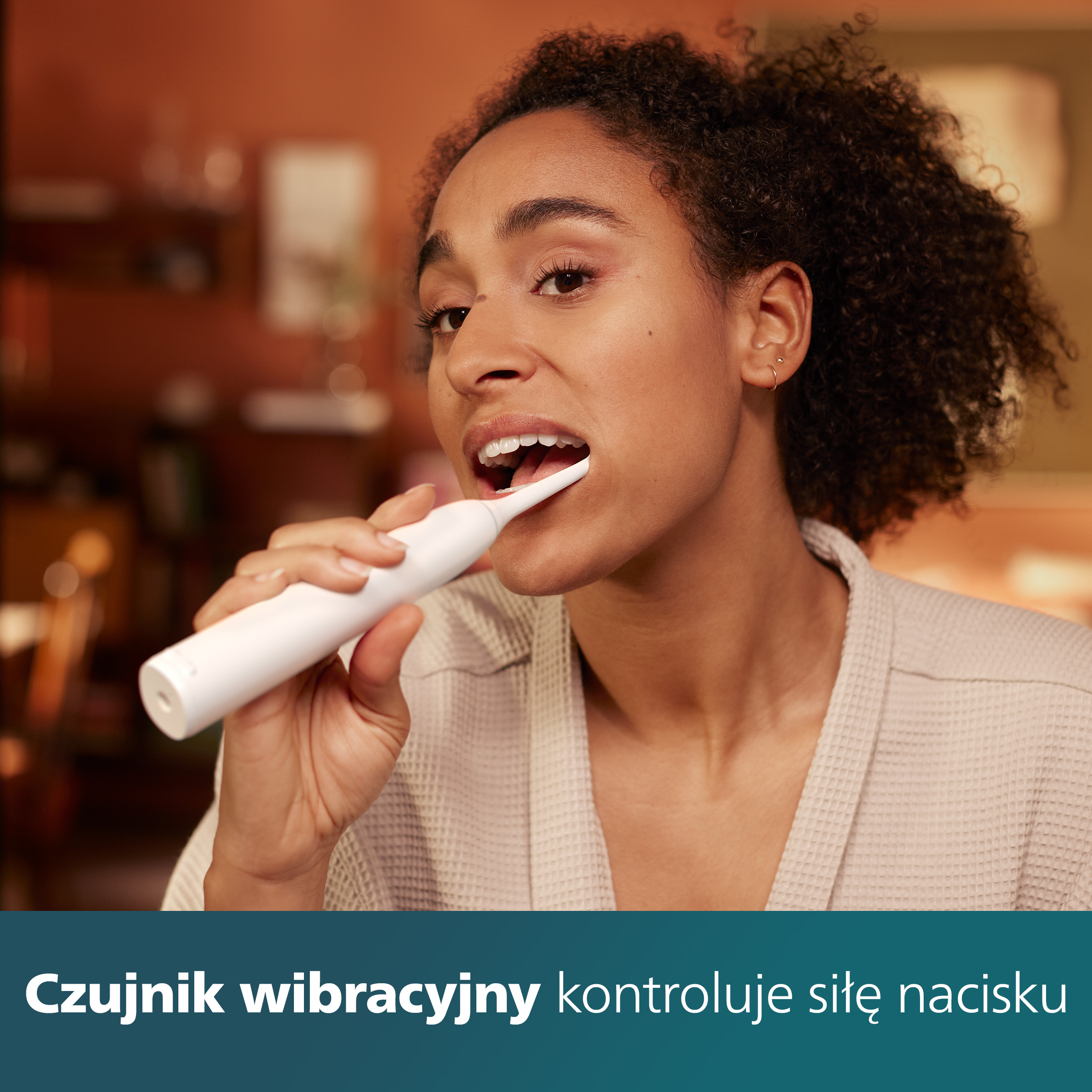 Kobieta myjąca zęby białą szczoteczką przed lustrem.