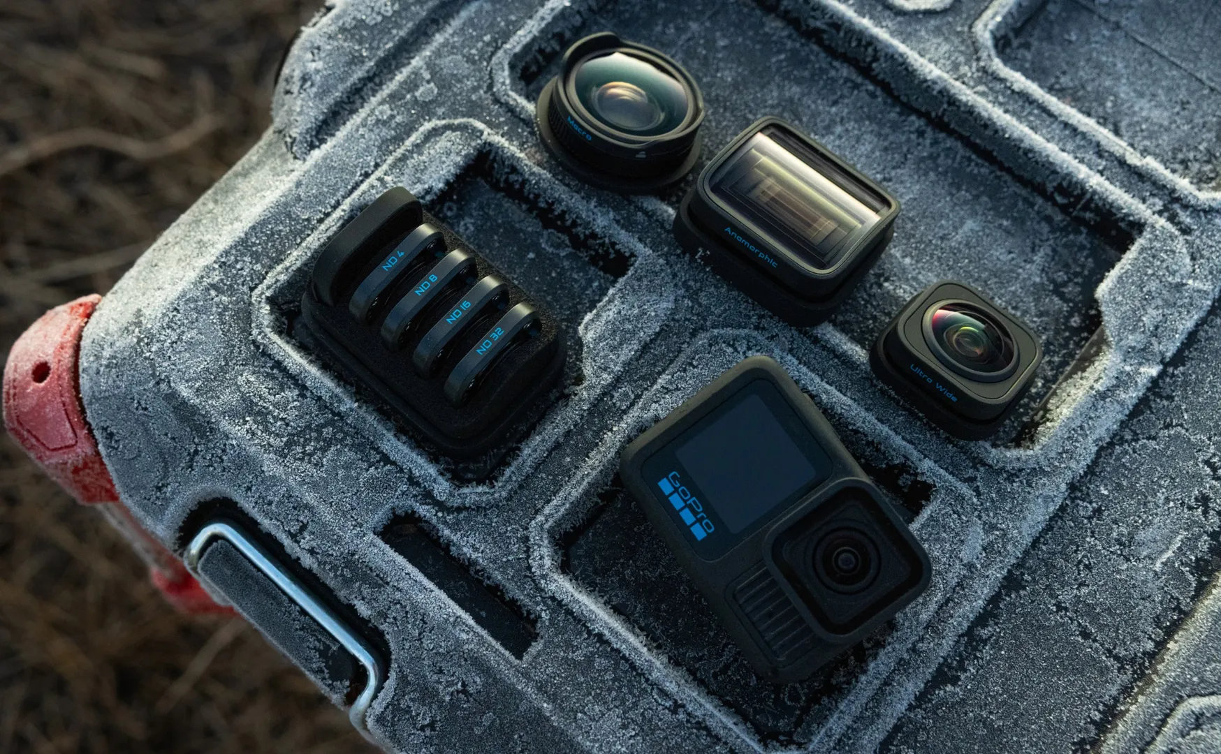 Aparat, obiektywy i filtry na pokrytej śniegiem szarej powierzchni. Elementy są dobrze zorganizowane.