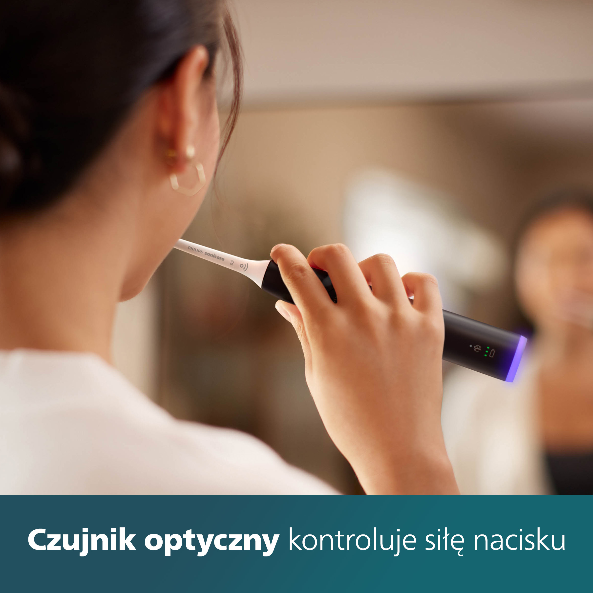 Kobieta myje zęby czarną szczoteczką Philips Sonicare. Lustro w tle.