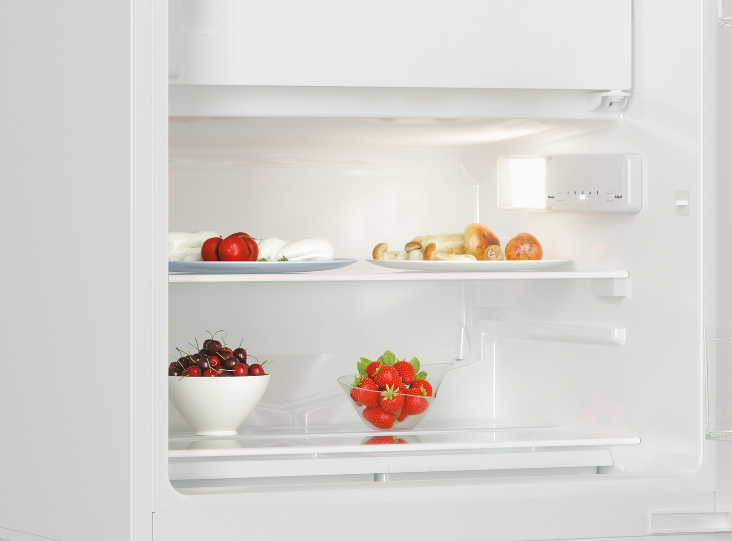Interior de la nevera con estantes: platos de comida, cuencos de cerezas y fresas.