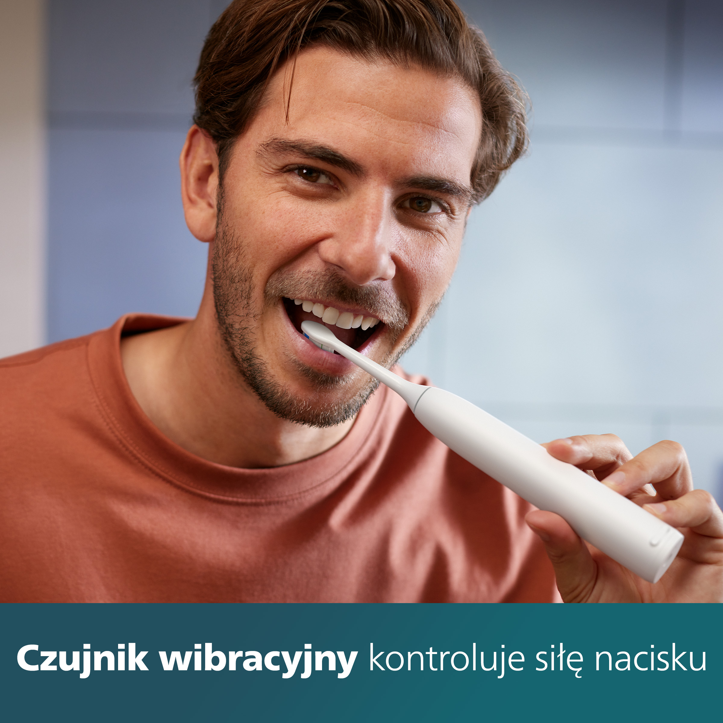 Mężczyzna myje zęby białą szczoteczką Philips Sonicare. Uśmiechnięta twarz.