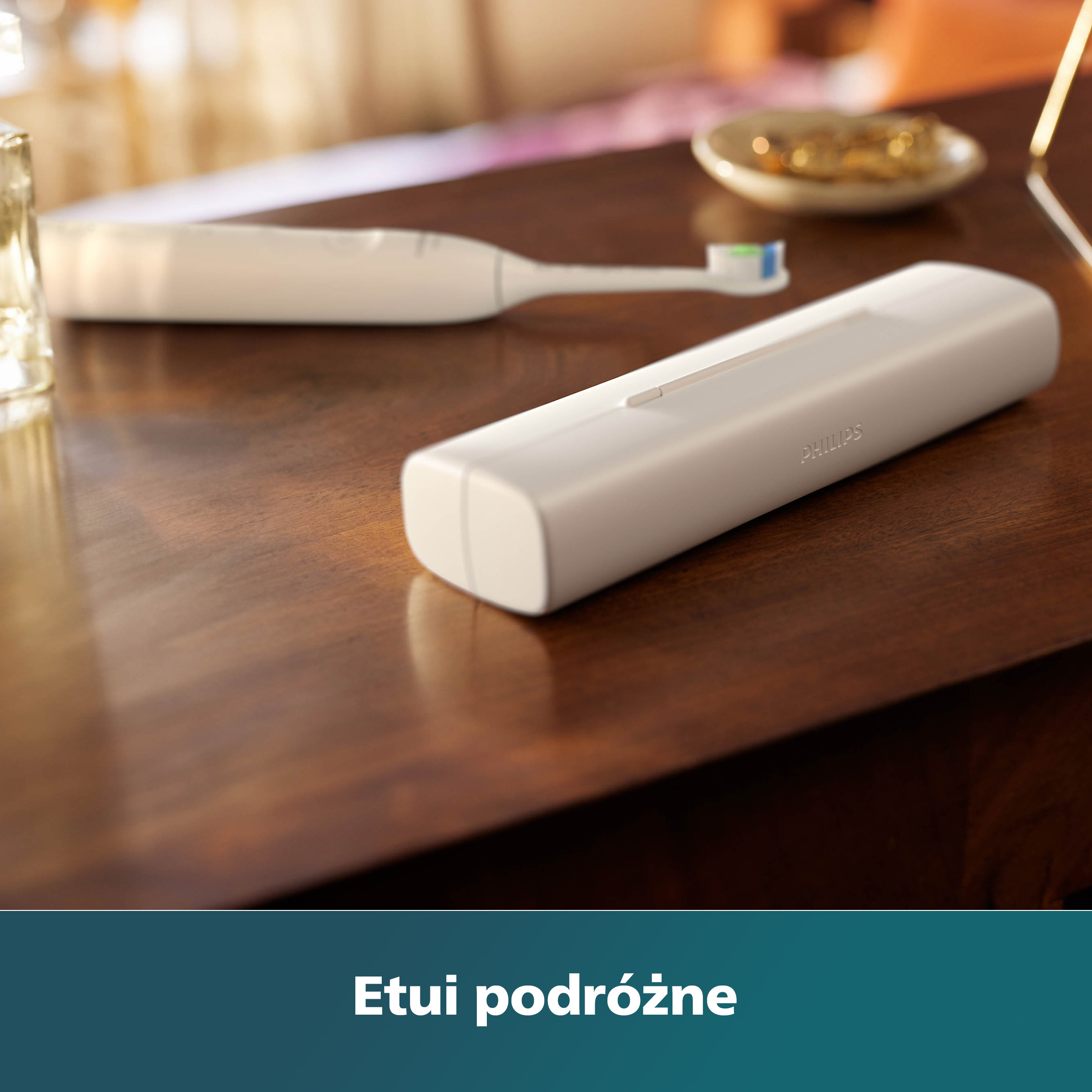 Biała szczoteczka Philips Sonicare i etui podróżne na drewnianym stole. Rozmyte tło.