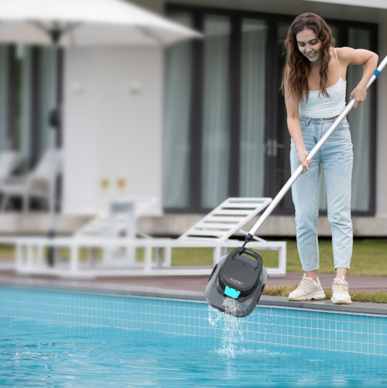 Kobieta używająca robota do czyszczenia basenu w basenie, trzymając kij.