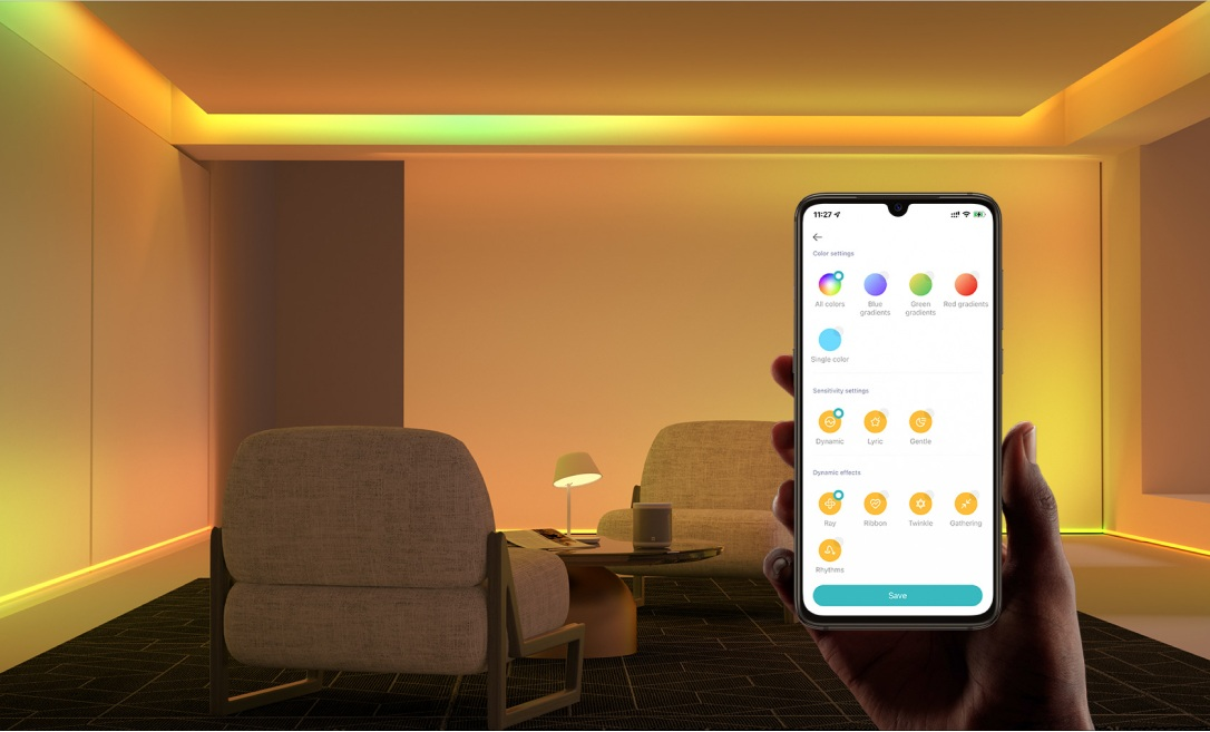 Dłoń trzymająca telefon z ustawieniami kolorów świateł w nowoczesnym salonie.