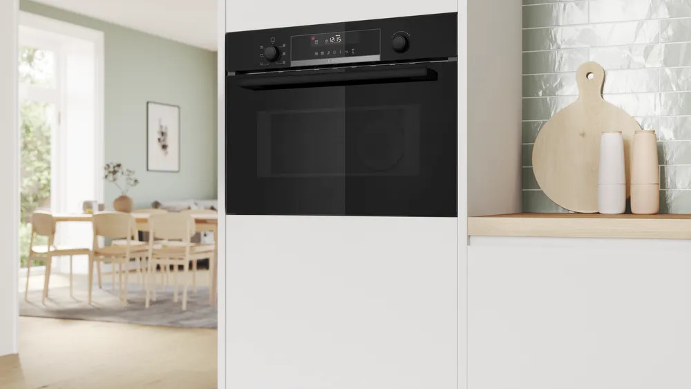 Zamknięty piekarnik w białej kuchni. Piekarnik jest czarny z cyfrowym wyświetlaczem.