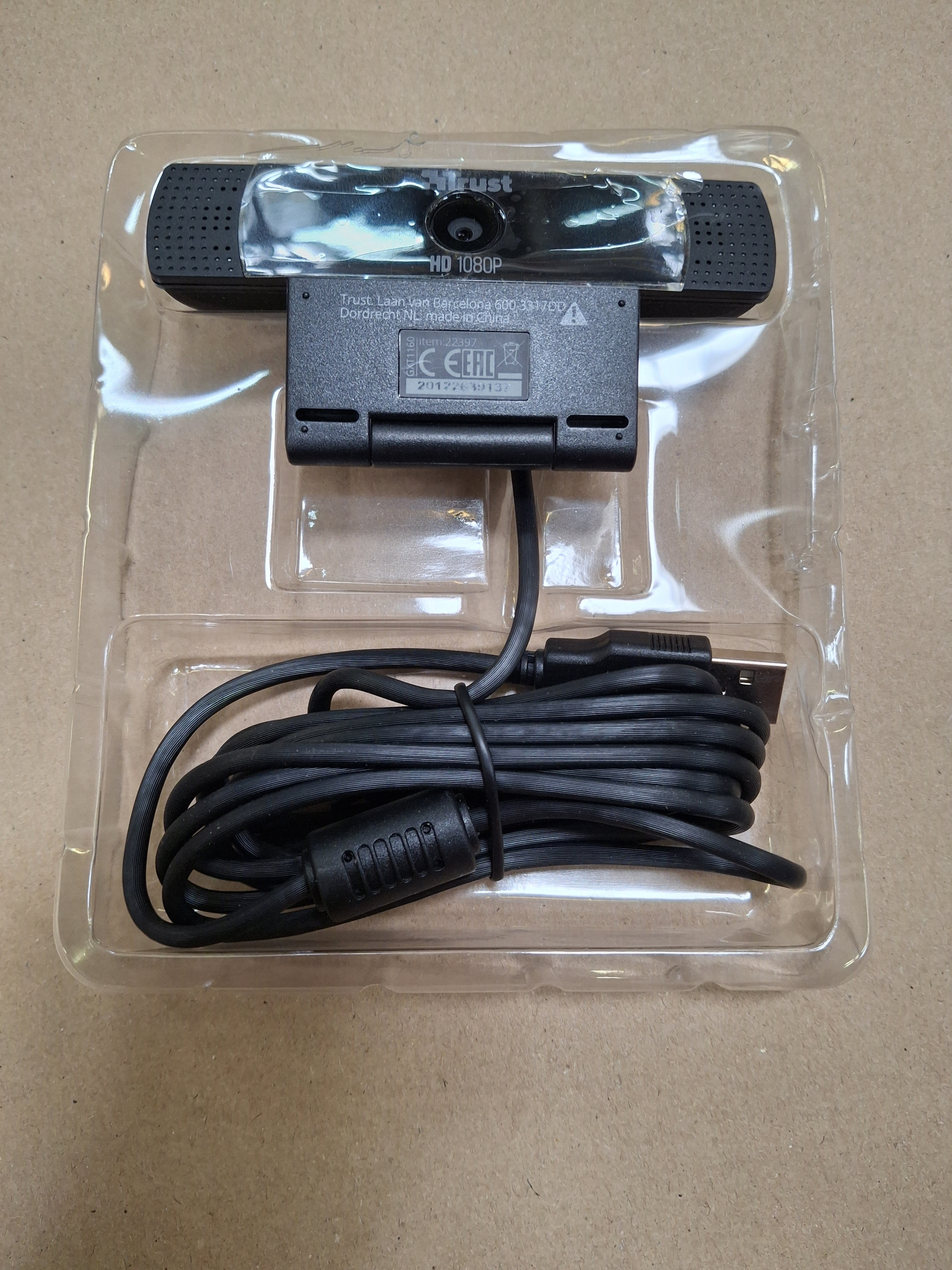 Kamerka internetowa Trust Vero. Czarna kamerka z kablem, w plastikowej tacce. Kamerka jest w tacy.