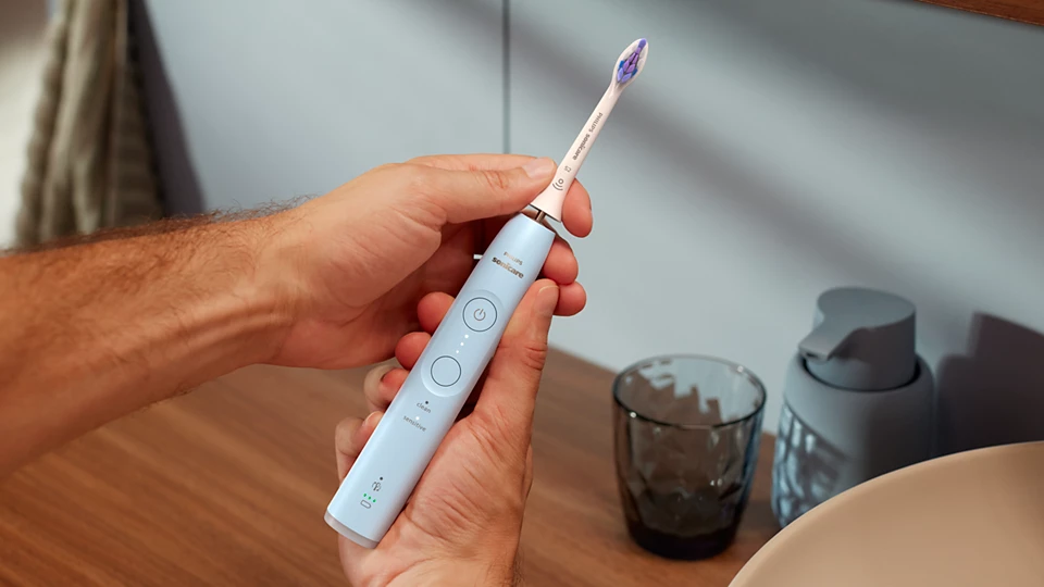 Személy kék elektromos fogkefét tart.