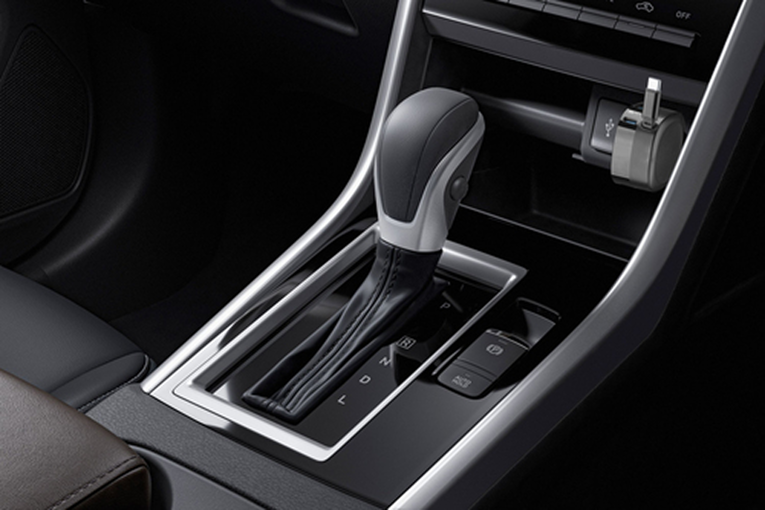 Interior del coche: palanca de cambios, transmisión automática, interior negro y un cargador enchufado.