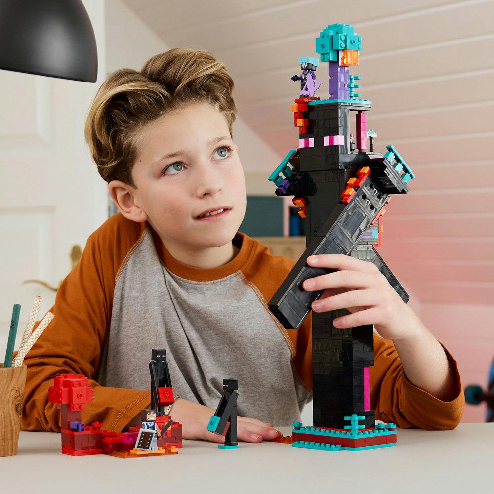Ein junger Junge betrachtet ein Lego Minecraft Set, das auf einem Tisch mit anderen Blöcken aufgebaut ist.