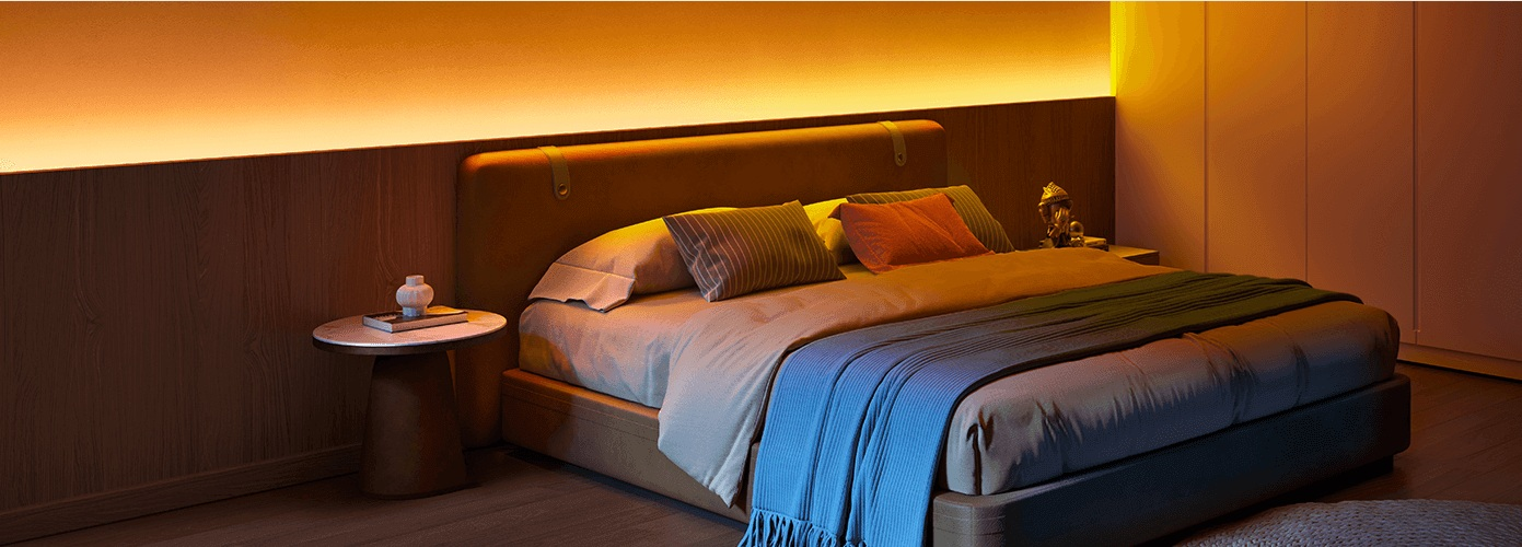 Scena sypialni z łóżkiem, poduszkami, kocem i stolikiem nocnym. Ciepłe oświetlenie i drewniane panele tworzą przytulną atmosferę.