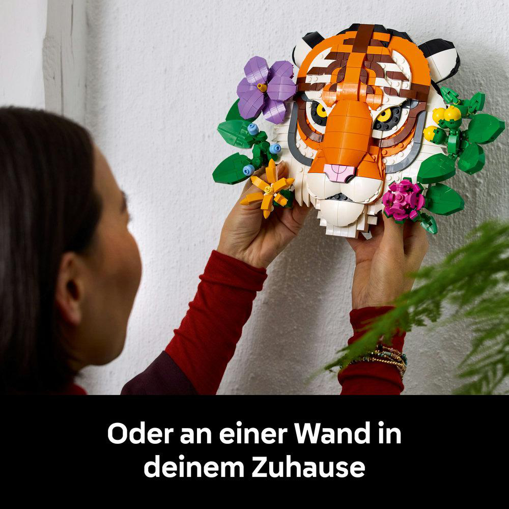 Frau hängt LEGO-Tigerkopf mit Blumen an eine Wand in ihrem Zuhause.