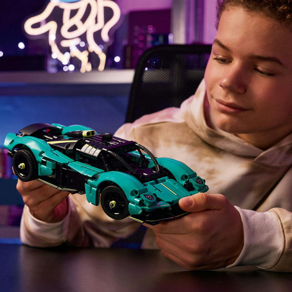 Ein junger Junge hält ein Lego Aston Martin Valkyrie Modellauto in Teal.