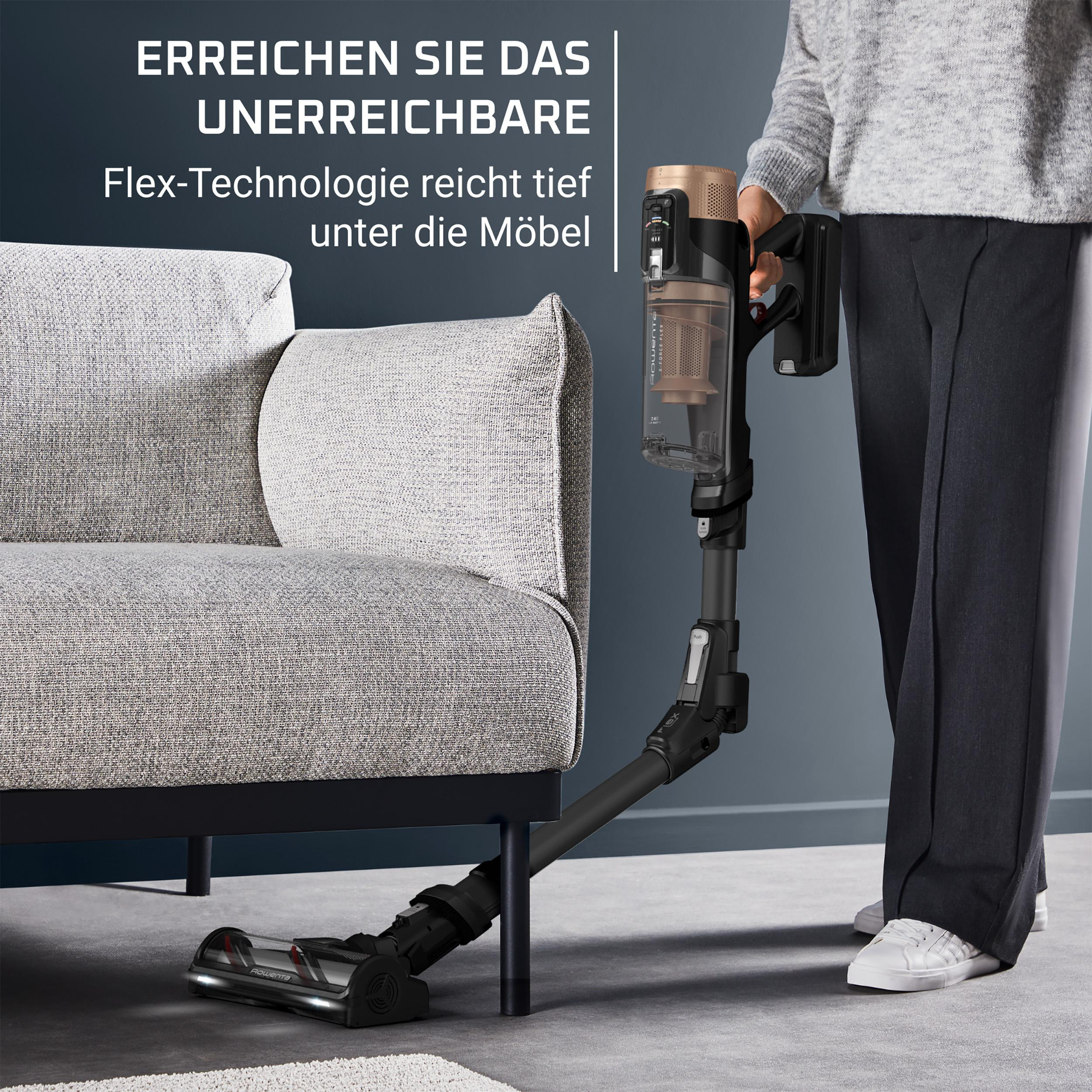 Eine Person saugt mit einem Staubsauger mit Flex-Technologie unter einem Sofa. Der Staubsauger ist schwarz und gold.