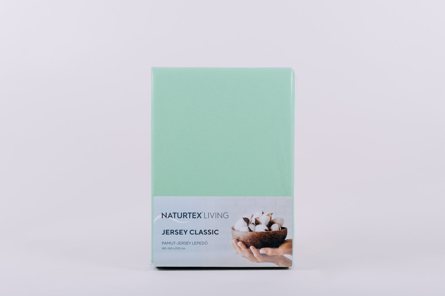 Mentaszínű lepedő csomagban. Fehér háttér. Szöveg: Jersey Classic. Kép a pamutról tálban.