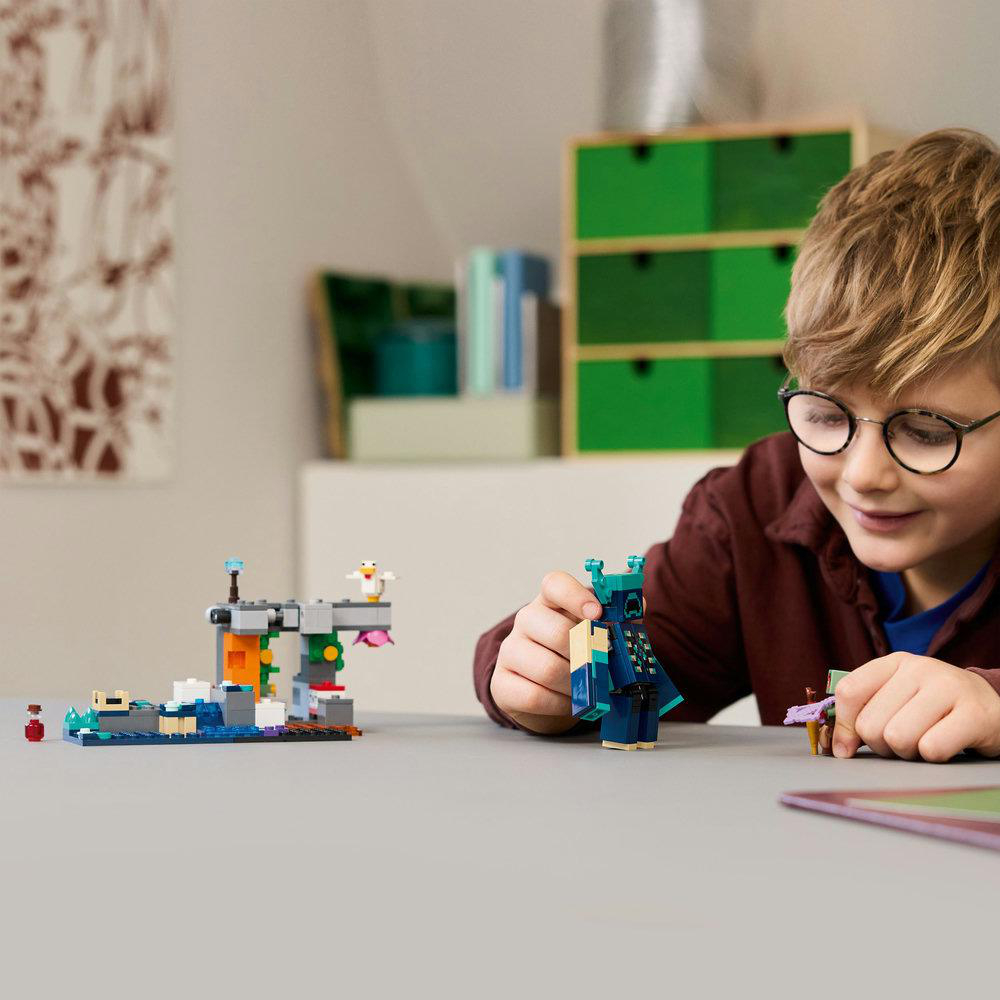 Junge spielt mit LEGO Minecraft Set. Blaue Wächterfigur, LEGO Struktur und Blöcke.