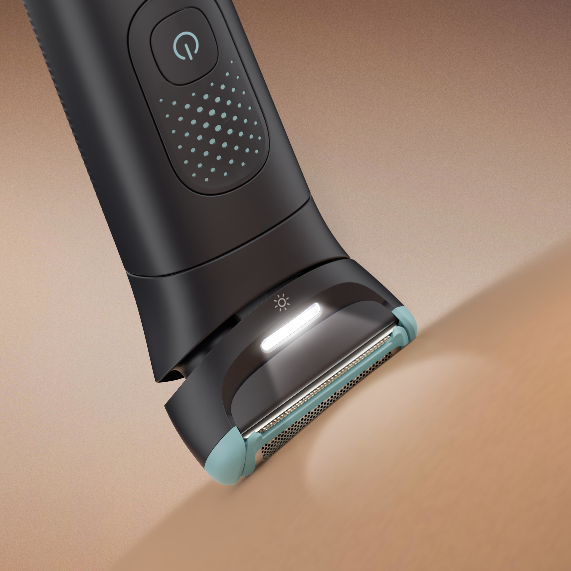 A Philips Body Groomer fejének közeli képe. Fényt, pengéket és kék díszítéseket mutat barna háttéren.