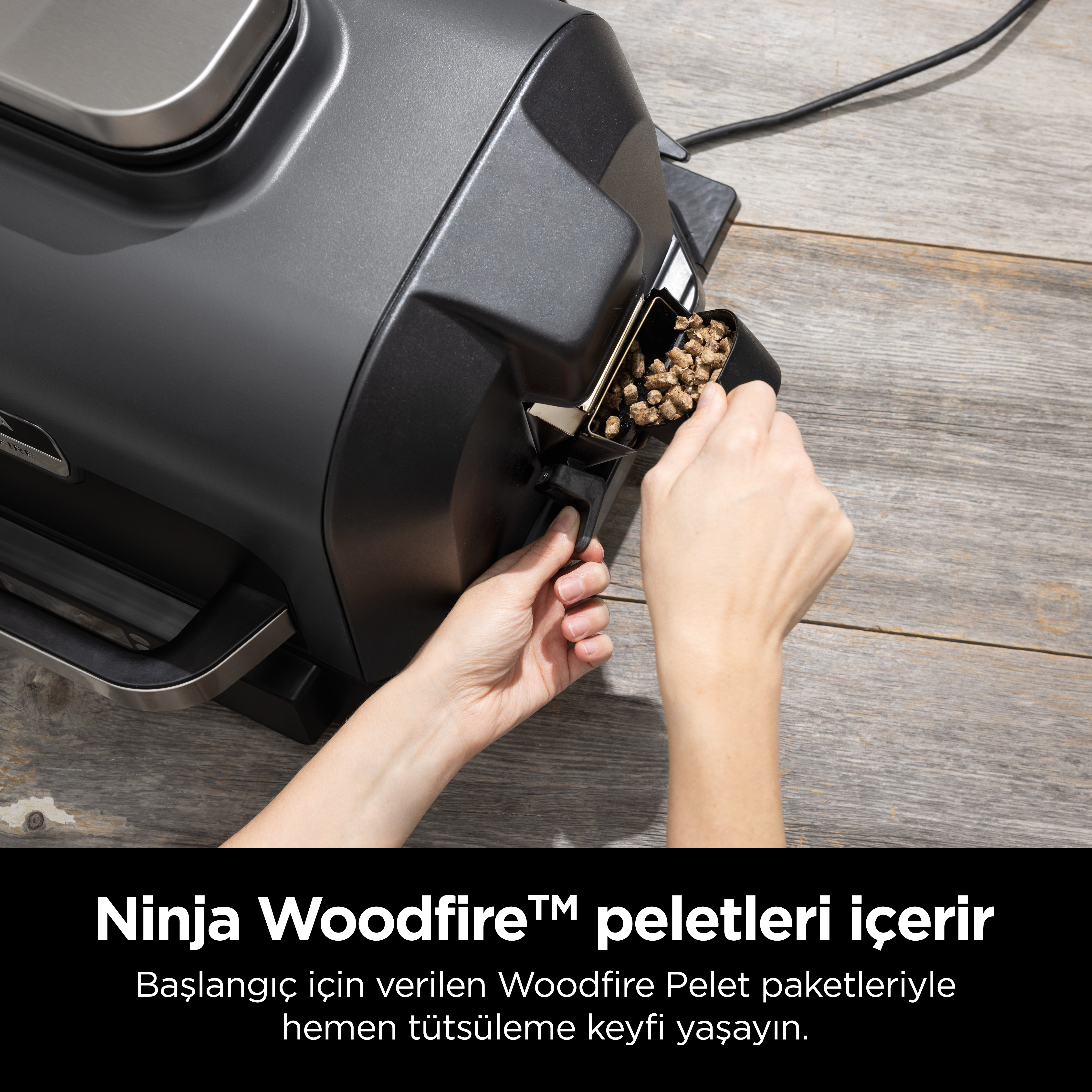 Bir kişi, ızgaraya woodfire peletleri yüklüyor. Metin yerleşimi: Ninja Woodfire peletleri.