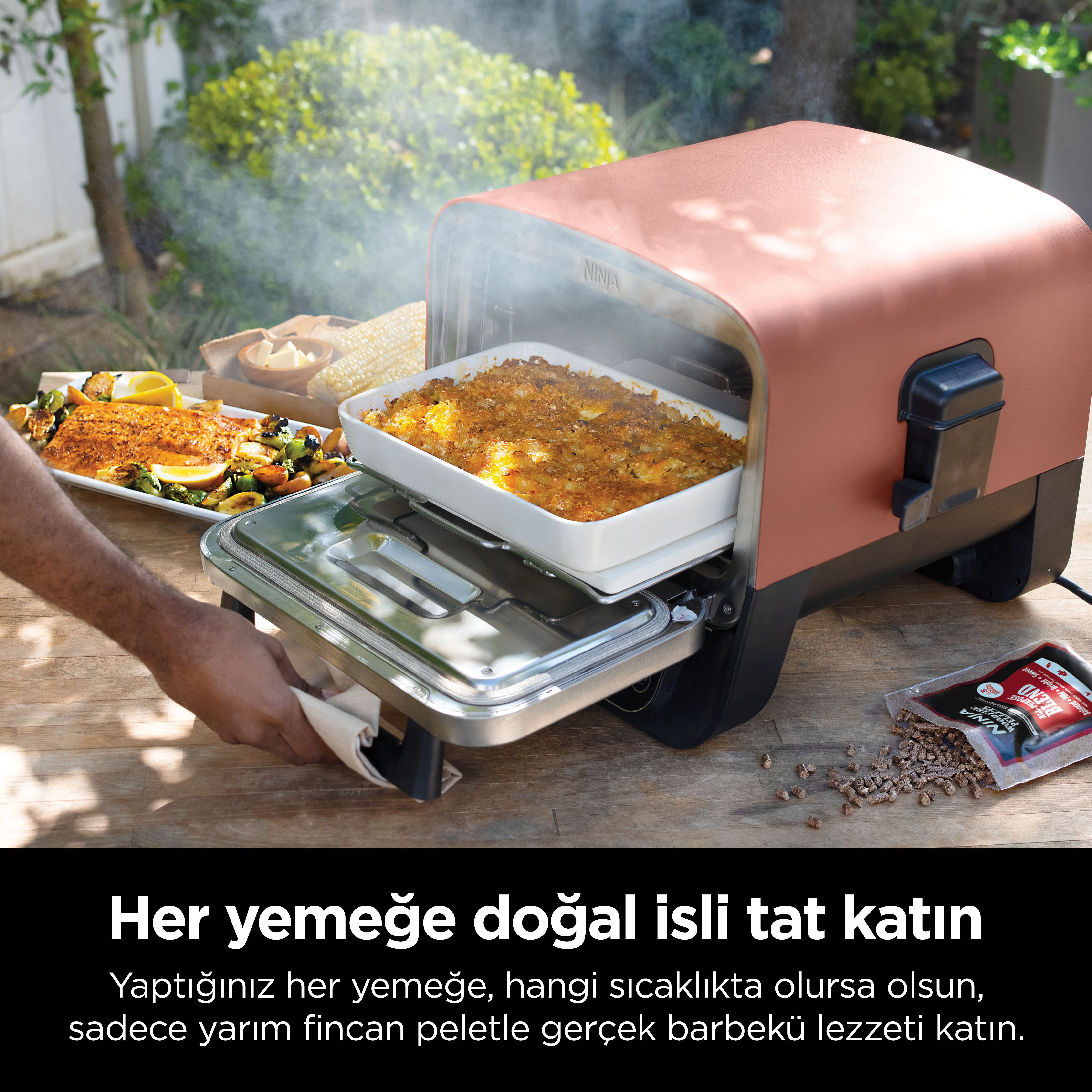 Bir kişi, bir ızgaradan bir güveç çıkarıyor. Metin: Herhangi bir yiyeceğe dumanlı lezzet katın.