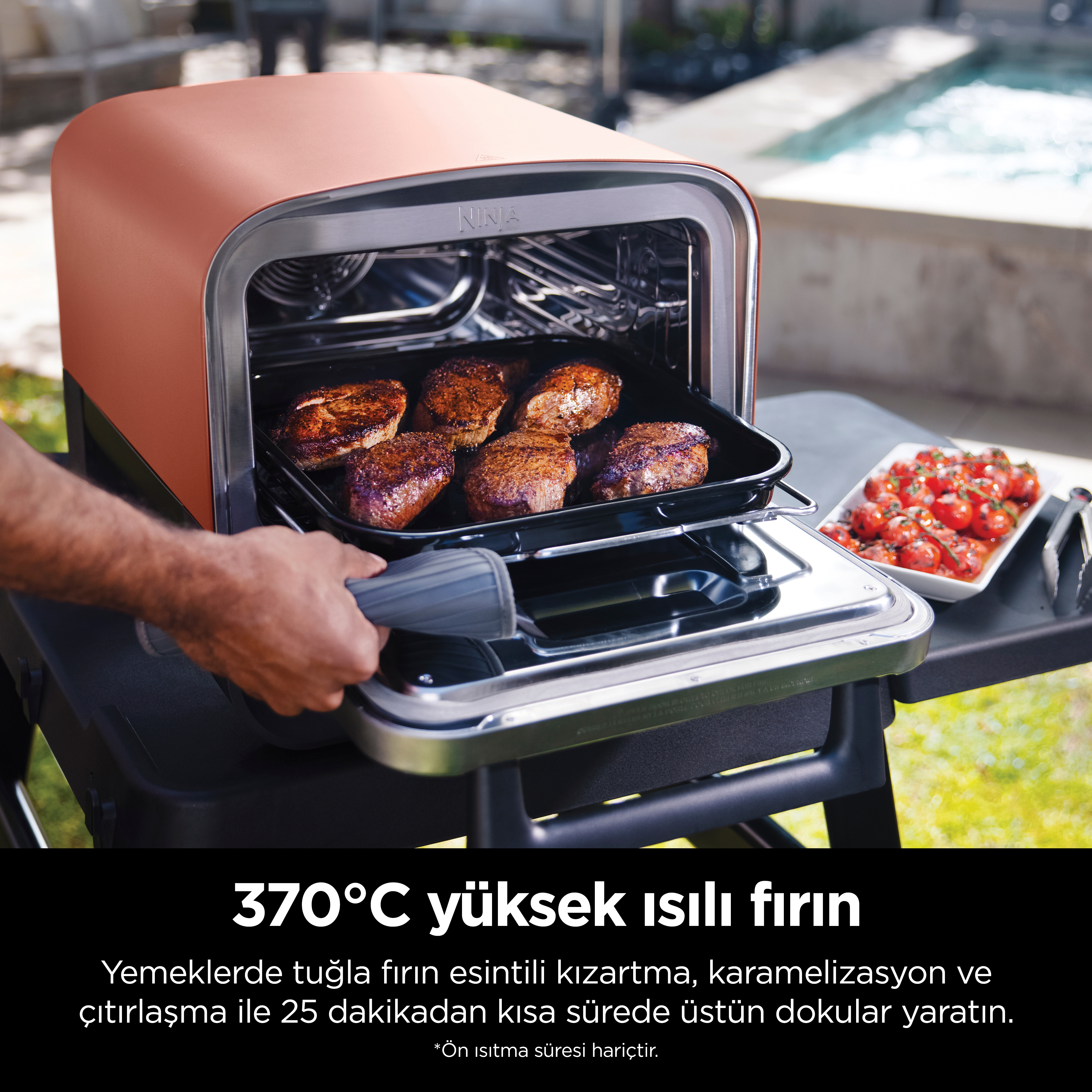 Bir kişi, ızgaradan pişmiş tavukla dolu bir tepsiyi çıkarıyor. Metin: 370°C'de yüksek ısı fırını.