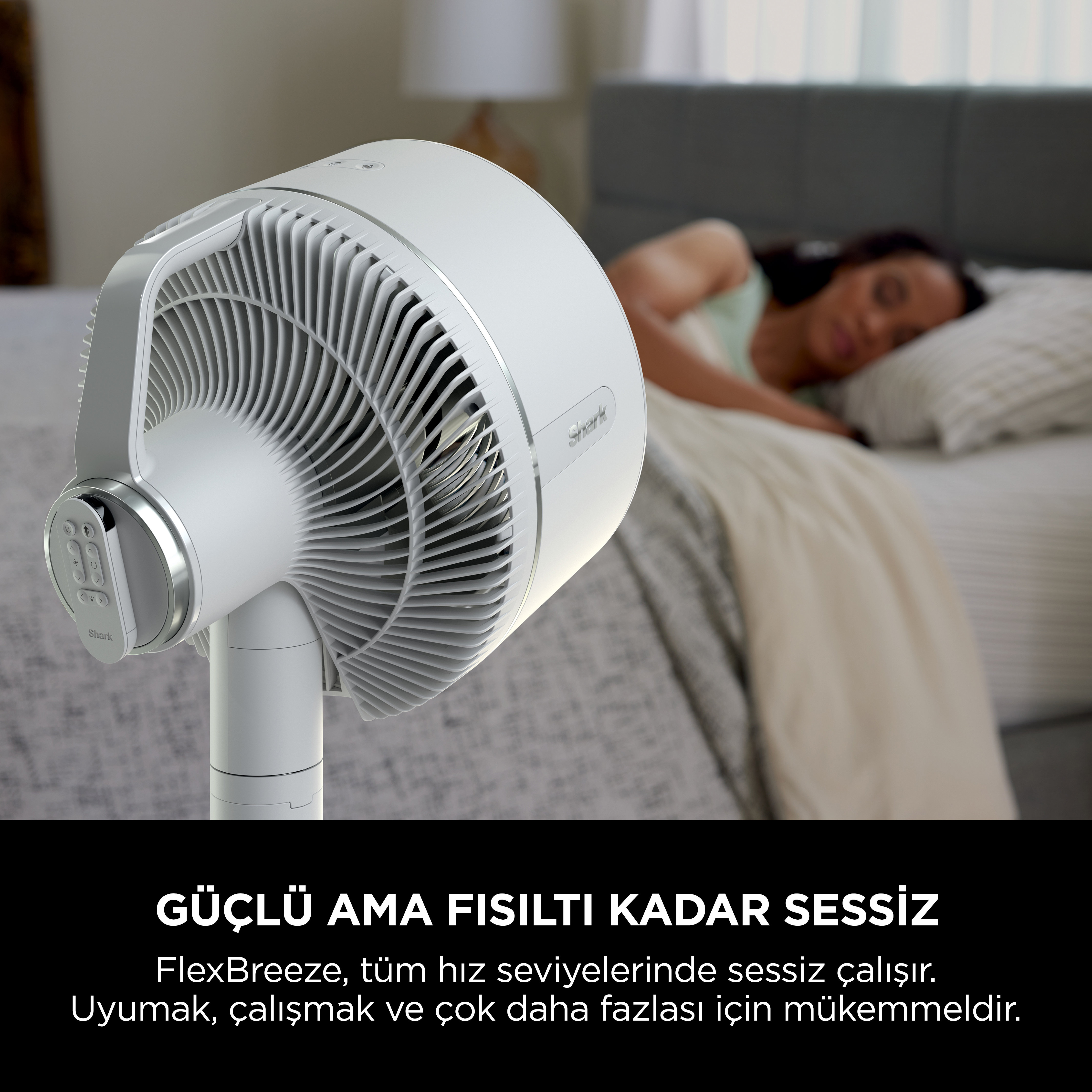 Yatakta uyuyan bir kişinin yanında beyaz bir vantilatör.