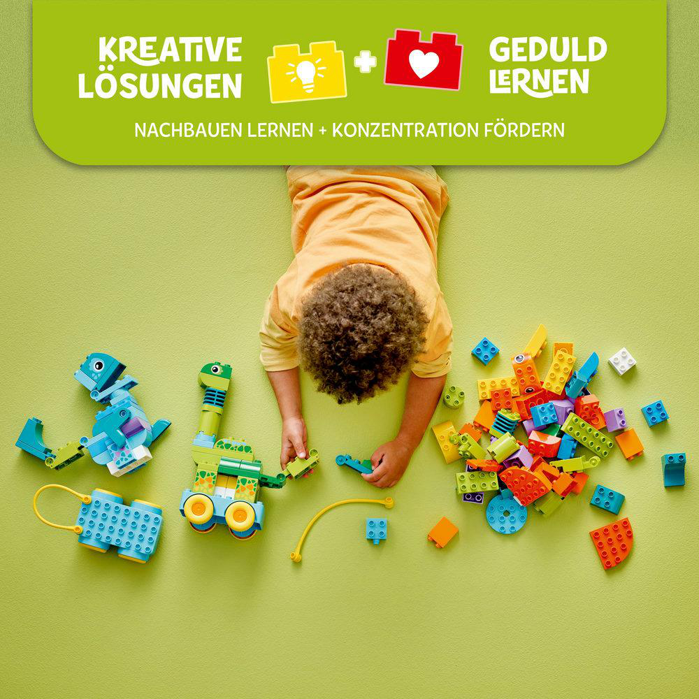 Ein Kind baut verschiedene Dinosaurier-Spielzeuge aus Lego Duplo-Steinen auf Grün.