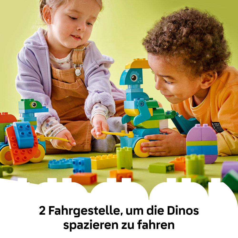 Zwei Kinder spielen mit Dinosaurier-Blockspielzeugen und bauen mit bunten Blöcken auf einer grünen Oberfläche.
