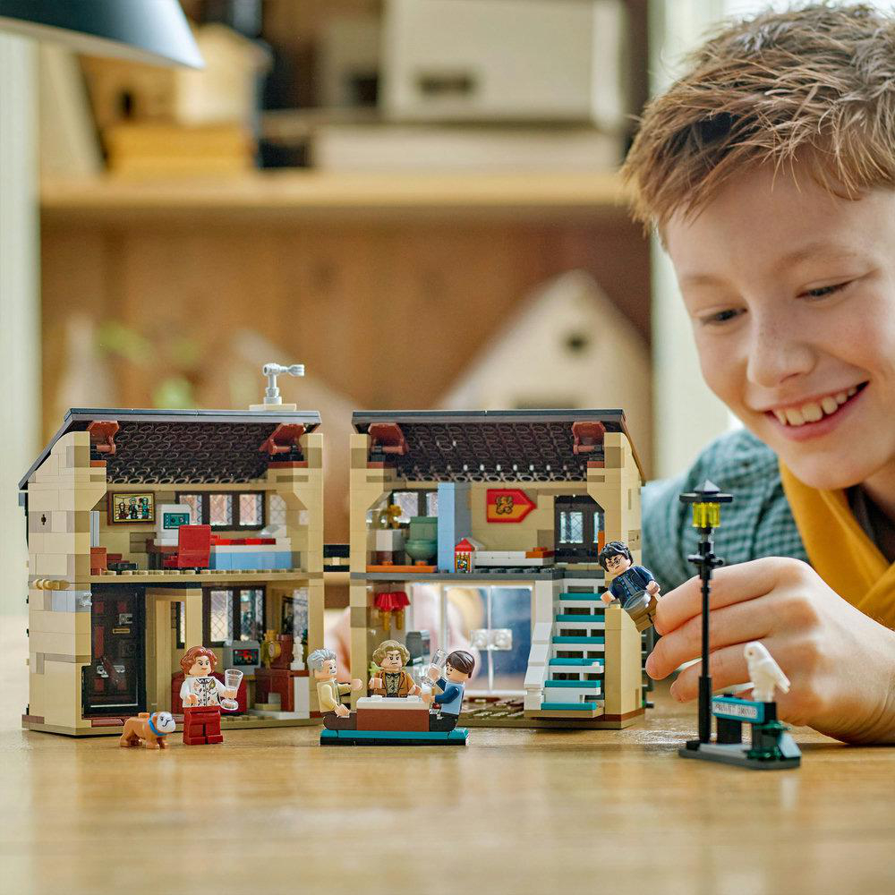 Ein Junge lächelt über ein Lego Harry Potter Set. Das Set ist ein Haus mit Figuren.