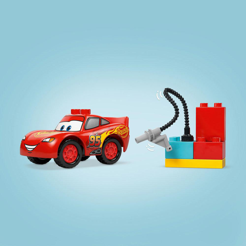 Rotes Spielzeugauto und Lego Duplo-Blöcke. Ein flexibler schwarzer Schlauch ist angeschlossen.