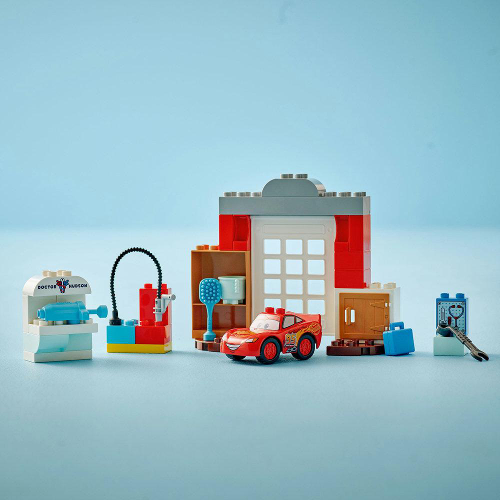 Lego Duplo Set mit rotem Auto, Gebäude und Werkzeugen. Doctor Hudson Schild ist sichtbar.