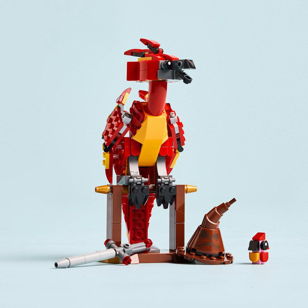 Lego-Phönix, rot, gelb und grau, auf einem braunen Ständer, mit einem Sortierhut und einer Minifigur.