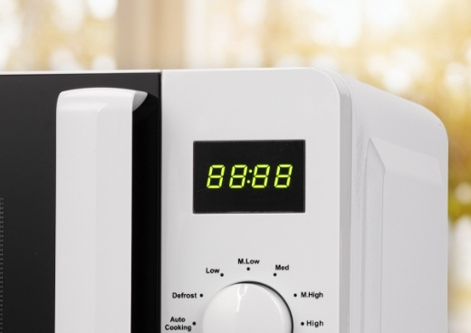 Wyświetlacz mikrofali pokazujący '88:88'. Biała mikrofala z panelem sterowania poniżej.