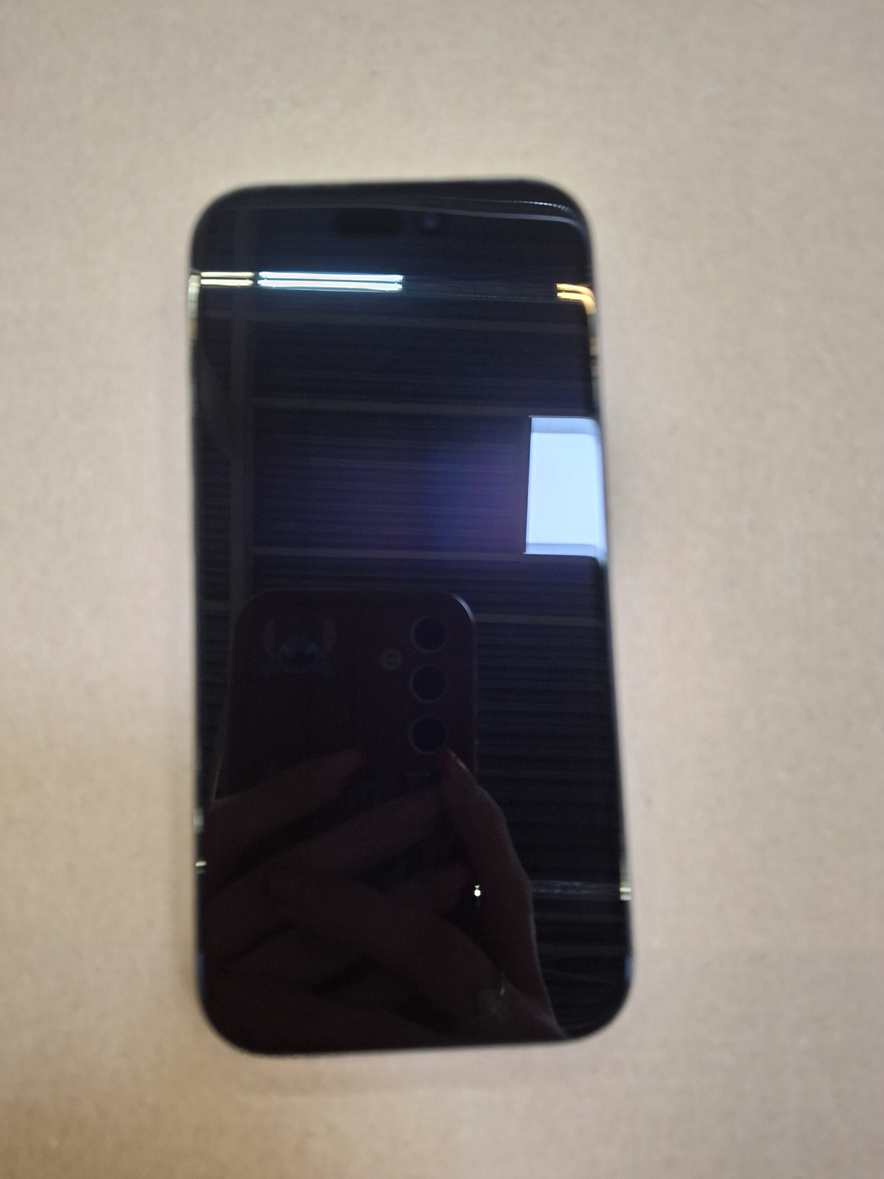 Czarny telefon, widok z przodu. Odbicie osoby widoczne na ekranie.