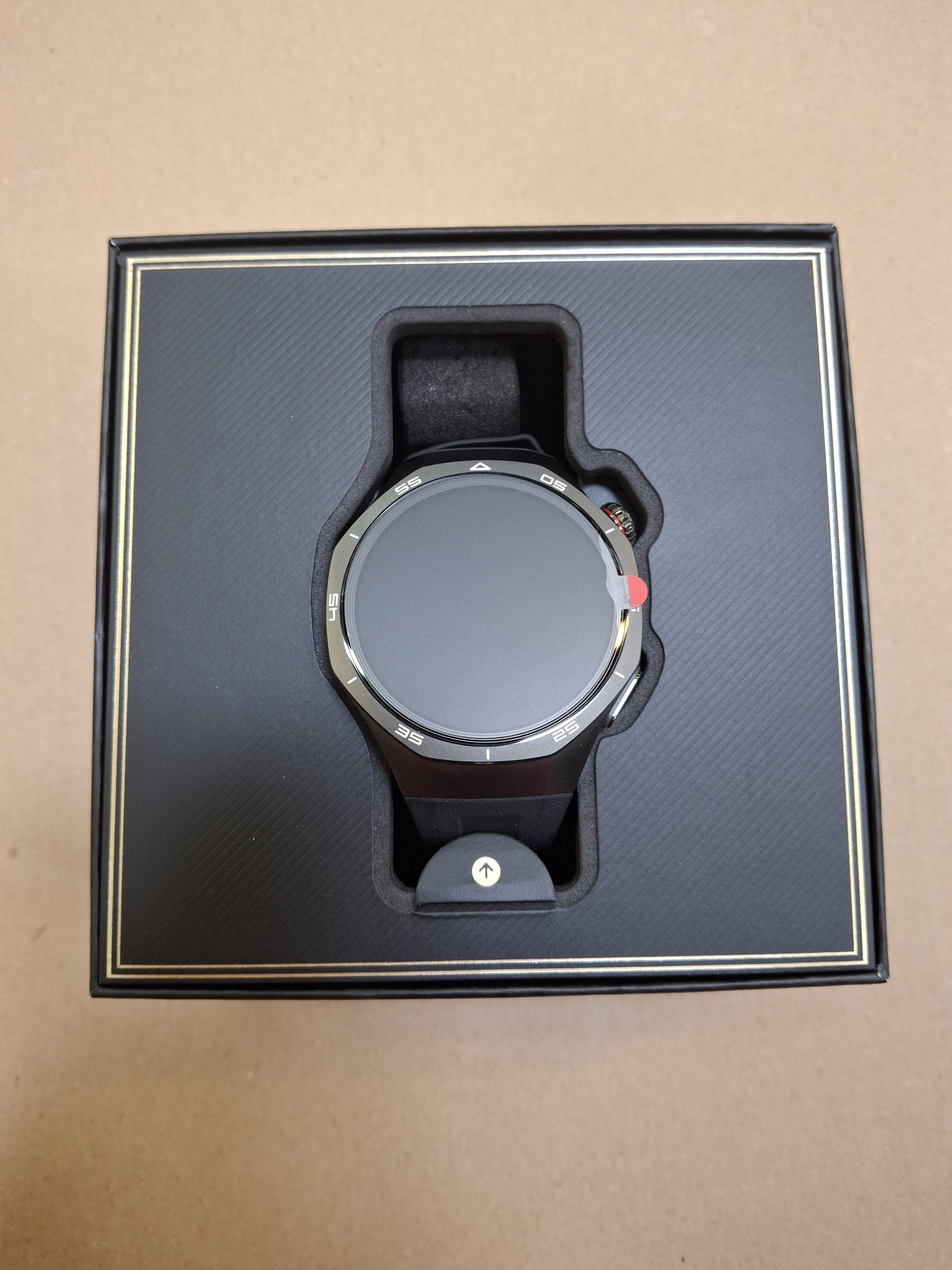 Czarny smartwatch Huawei w czarnym pudełku. Zegarek jest okrągły, z metalową ramką.