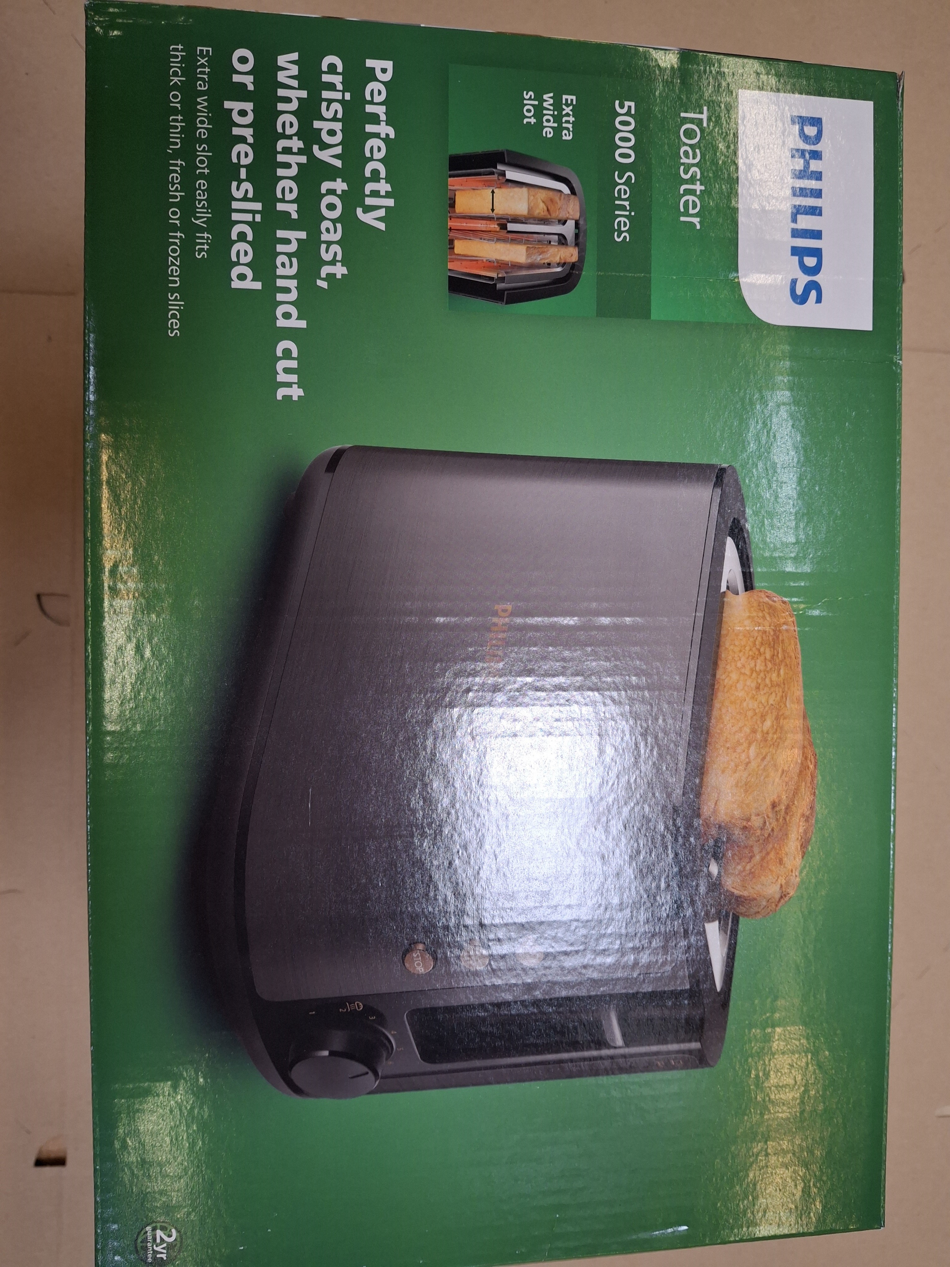 Pudełko na toster Philips z wystającym kawałkiem tost. Tekst: 'Idealnie chrupiący tost'.
