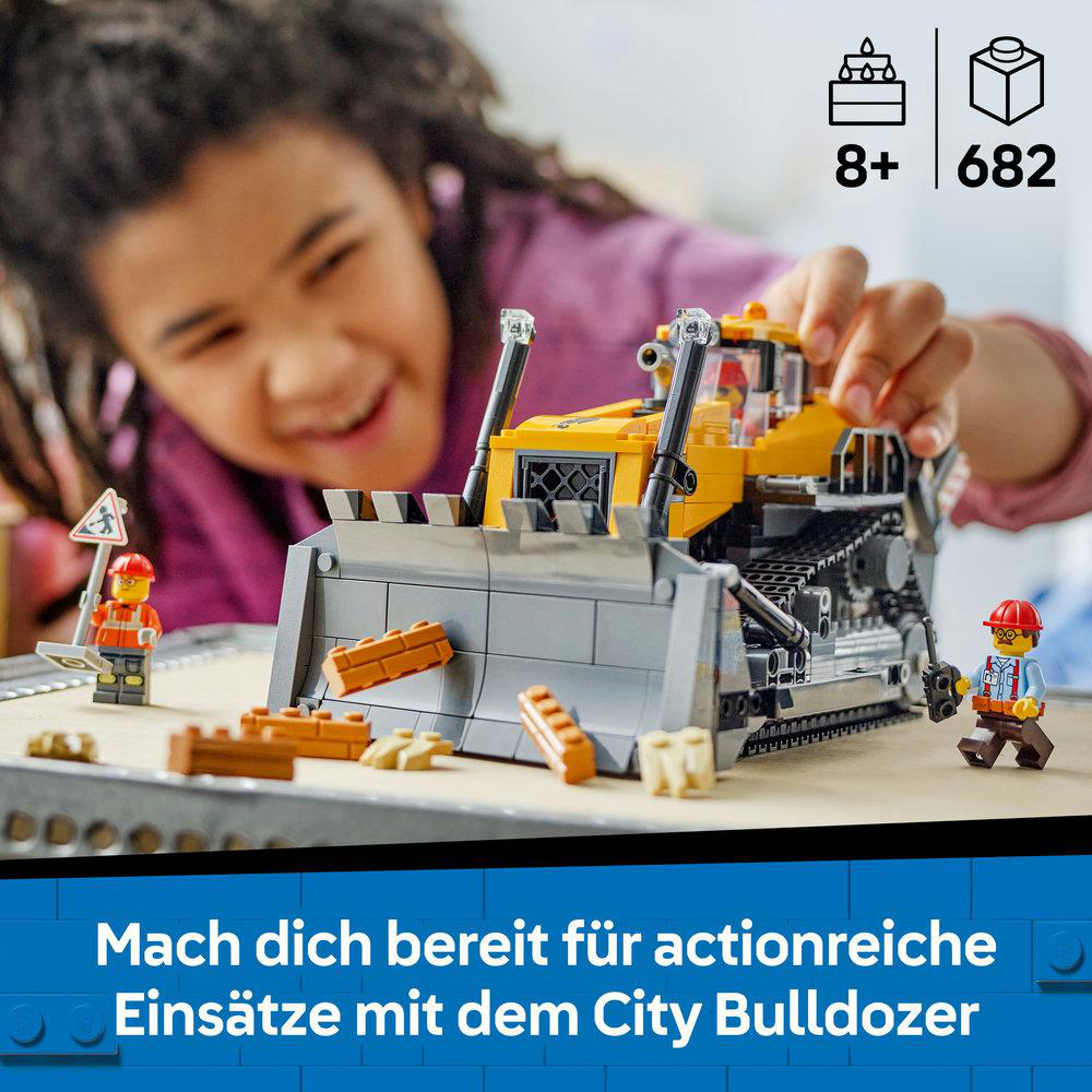 Ein Kind lächelt, während es mit einem Lego-Bulldozer spielt. Das Set enthält eine Mini-Figur und Bausteine. Blauer Hintergrund.