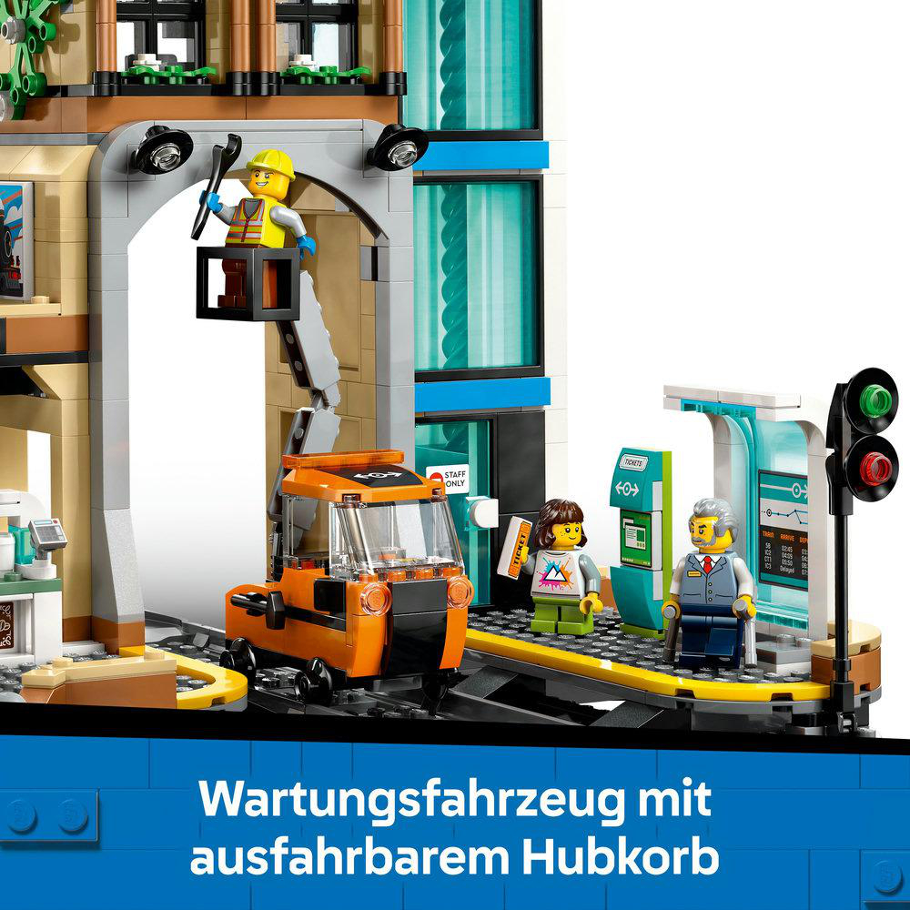 Ein Lego City Bahnhof-Set. Es zeigt ein Wartungsfahrzeug, Figuren und das Innere des Bahnhofs. Blauer Hintergrund.