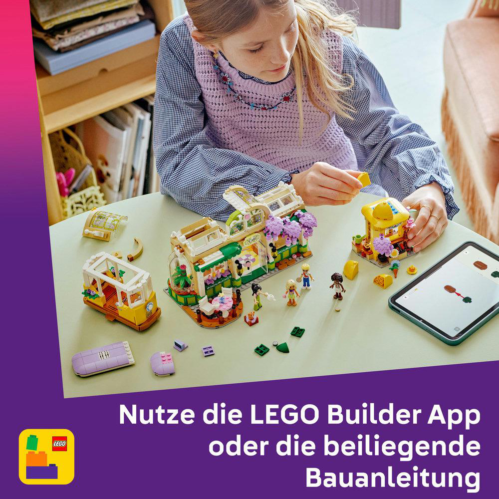 Ein Mädchen baut ein Lego-Set auf einem Tisch. Das Set enthält ein Café und eine Straßenbahn.