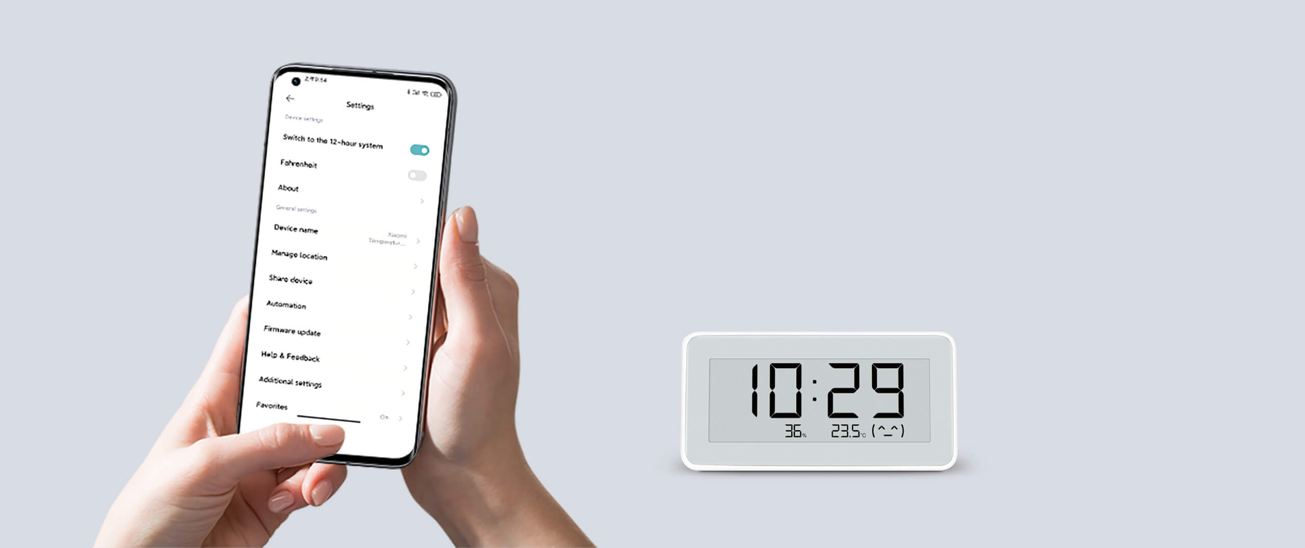 Ręka trzyma telefon z ustawieniami. Zegar wyświetla godzinę i temperaturę. Tło jest szare.