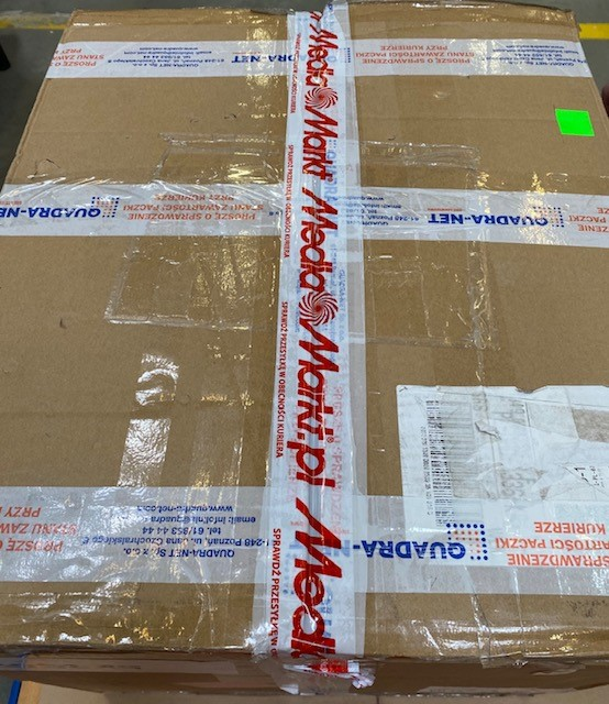 Widok z góry na zapieczętowany karton z taśmą Media Markt i etykietami wysyłkowymi.