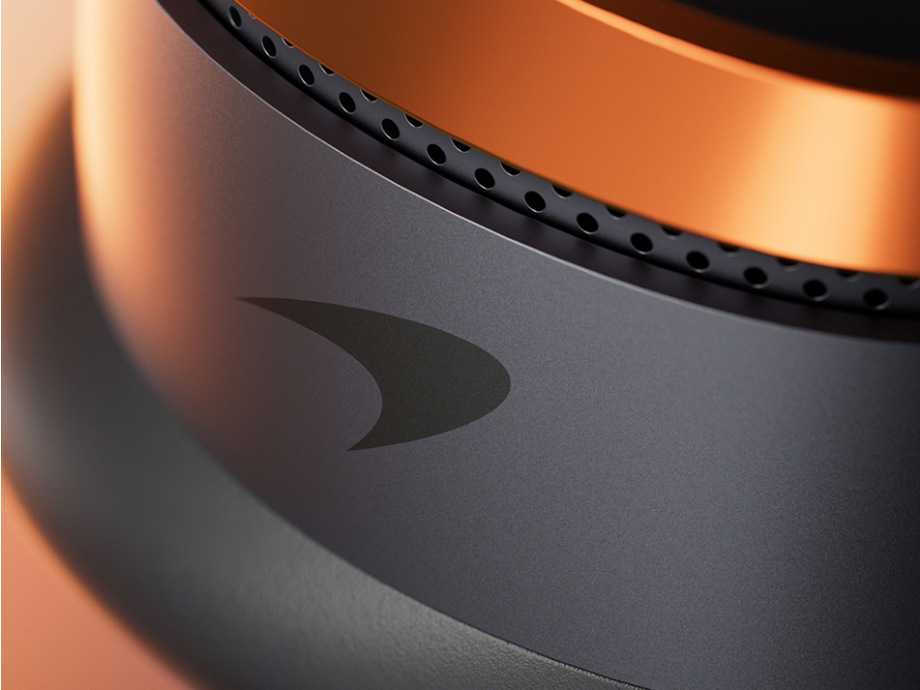 Zbliżenie słuchawki z logo McLaren i pomarańczowymi akcentami.