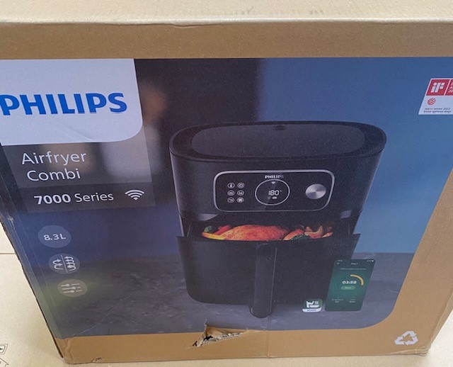 Philips Airfryer Combi w pudełku. Czarne urządzenie, jedzenie w środku. Pudełko pokazuje obraz i elementy sterujące.