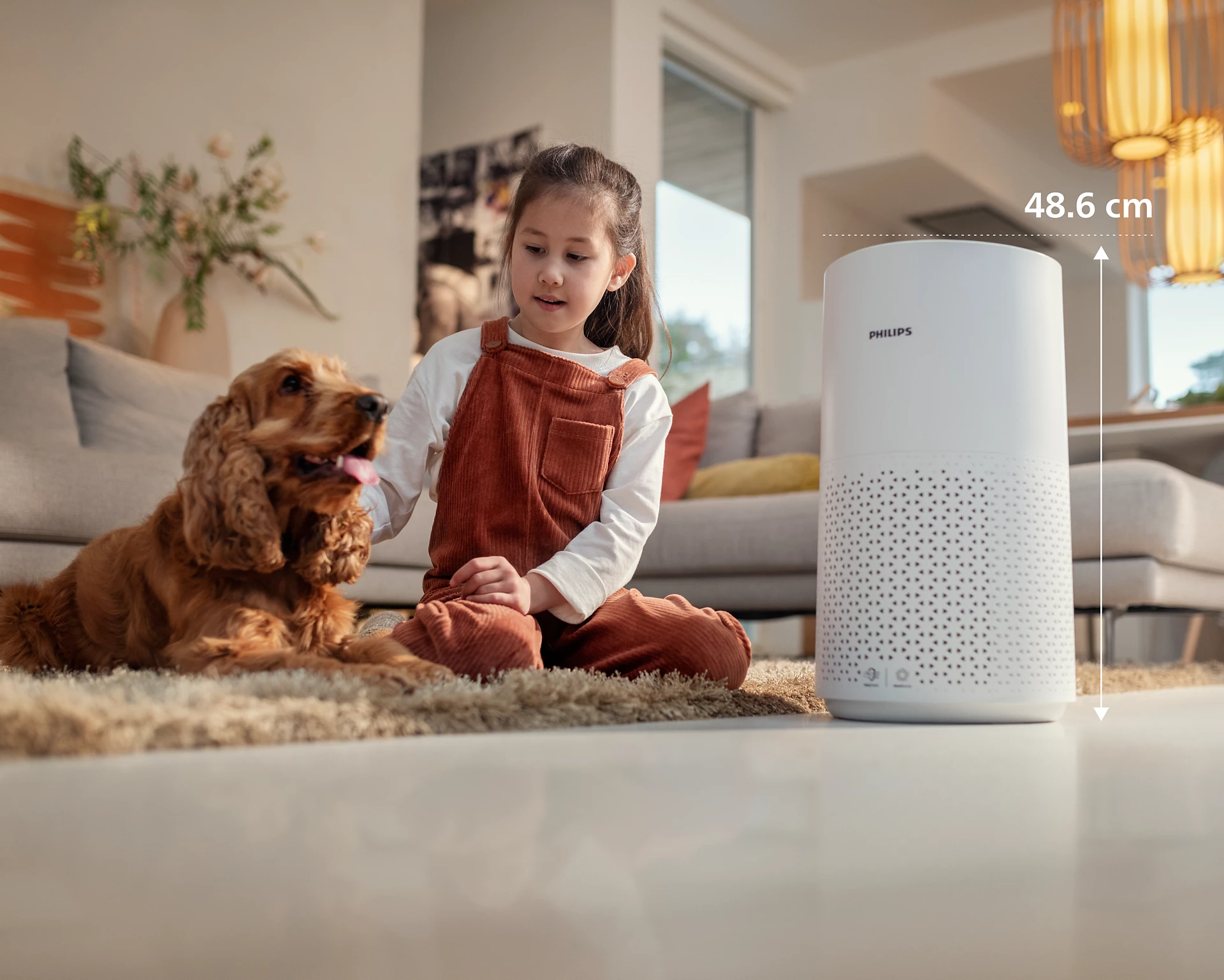 Lány és kutya ül egy Philips légtisztító mellett. A tisztító fehér, digitális kijelzővel.