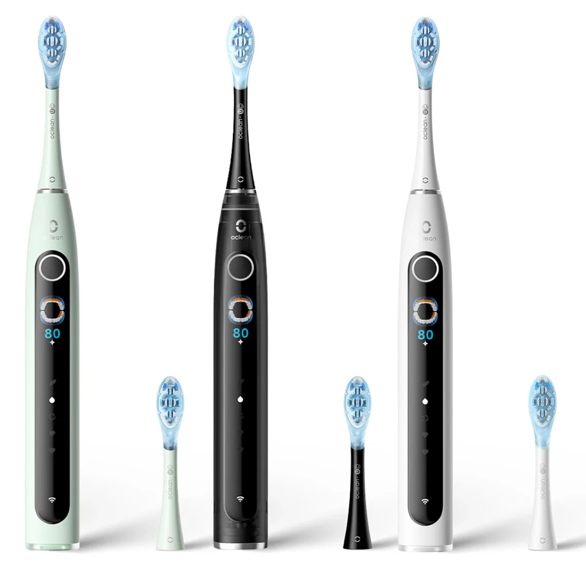 Trzy elektryczne szczoteczki do zębów w kolorze zielonym, czarnym i białym, każda z zapasową główką, na białym tle.