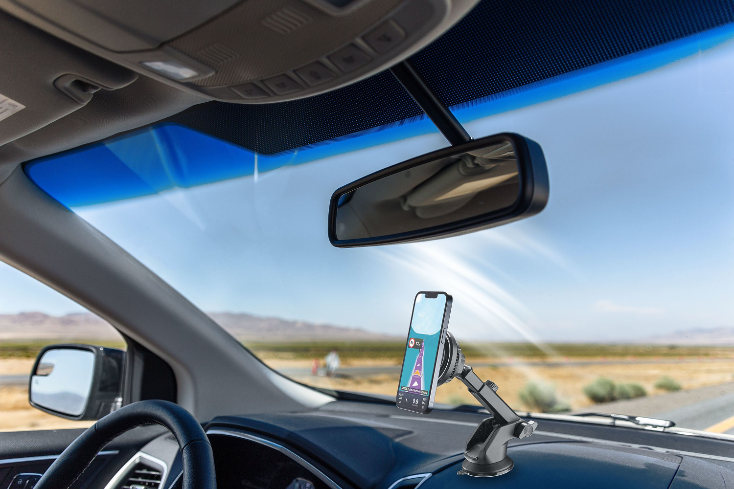Interior de un coche con un teléfono montado en el salpicadero mediante una ventosa. Se ve una carretera.