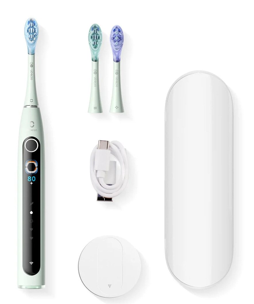 Zestaw zielonej elektrycznej szczoteczki do zębów z ładowarką, dodatkowymi główkami, kablem USB i białym etui podróżnym na białym tle.