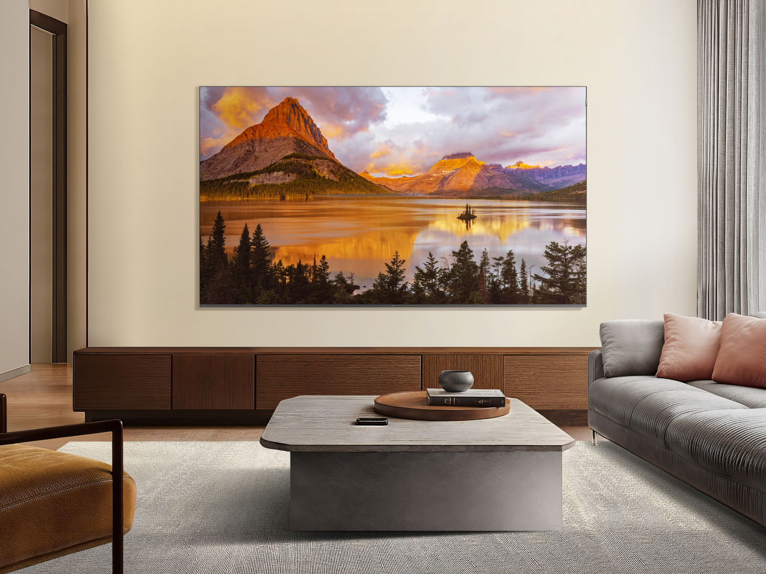 TV en una sala de estar, mostrando una puesta de sol sobre montañas y un lago. Mueble de madera.