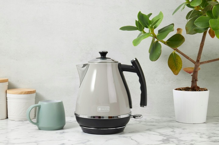 Szary czajnik Haden stoi na blacie. Kubek i roślina również znajdują się na blacie.