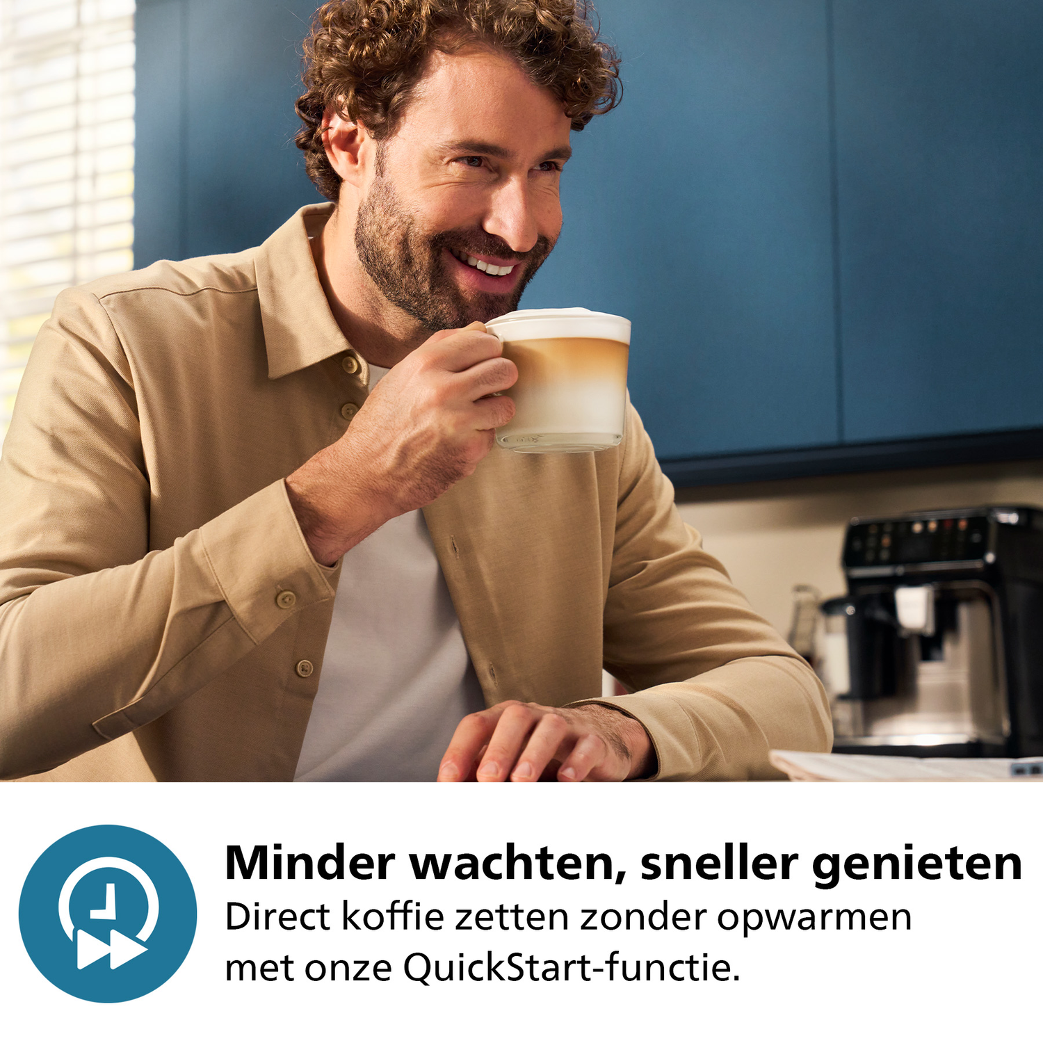 Man glimlacht, houdt een latte vast. Koffiemachine staat op de achtergrond.